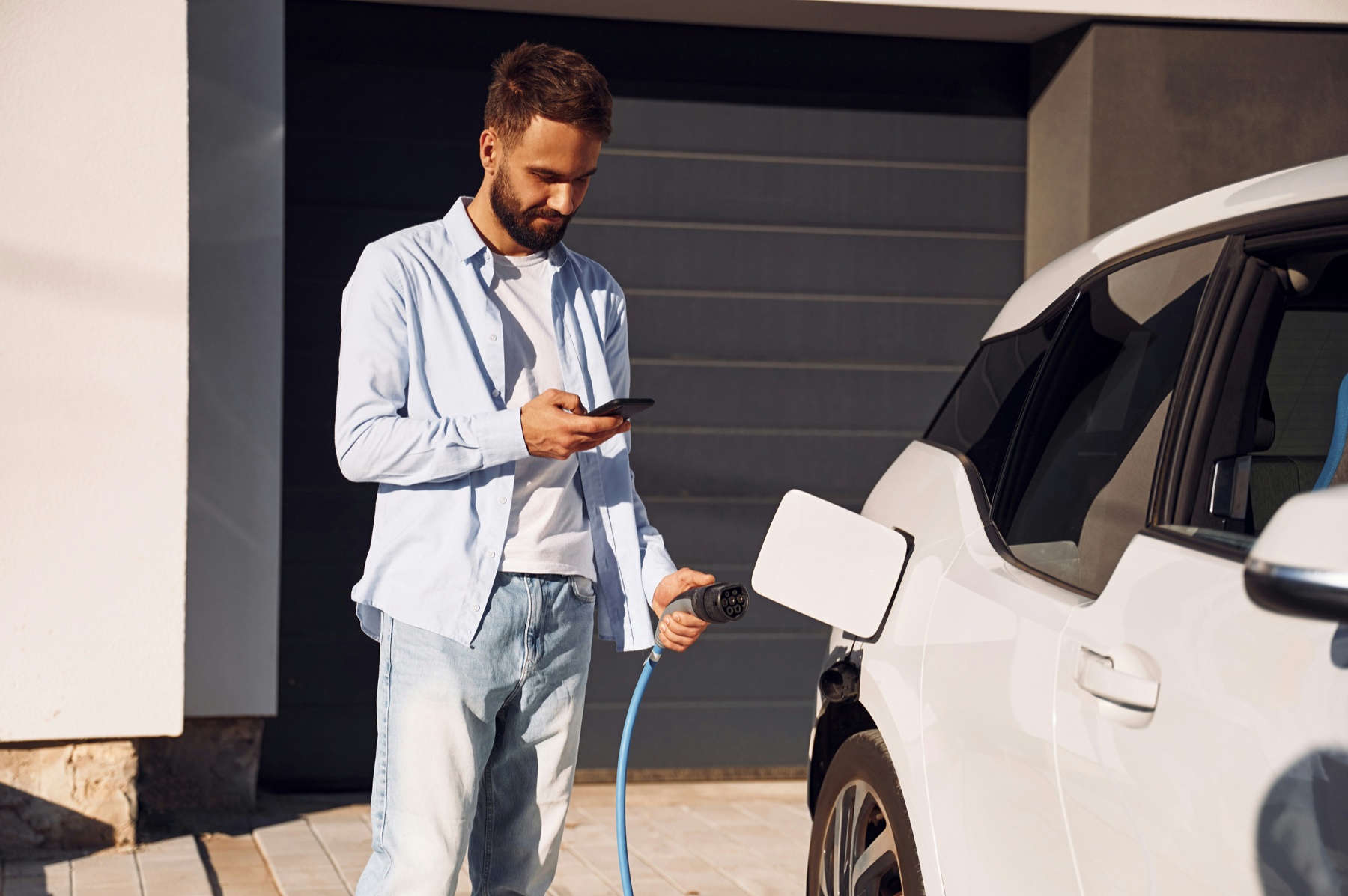 EV driver using a phone while preparing to charge at home
