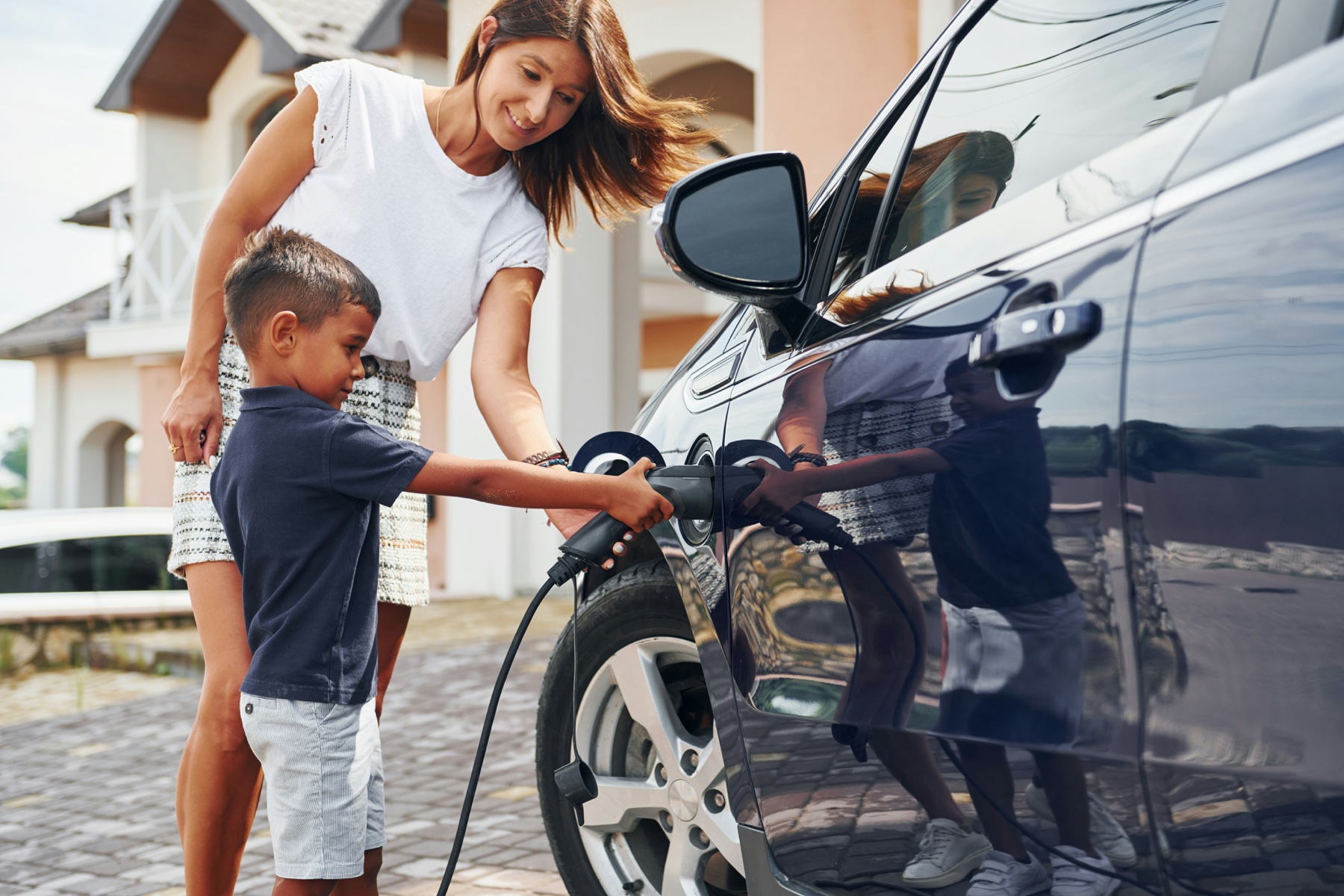A parent and child plugging in an EV at home